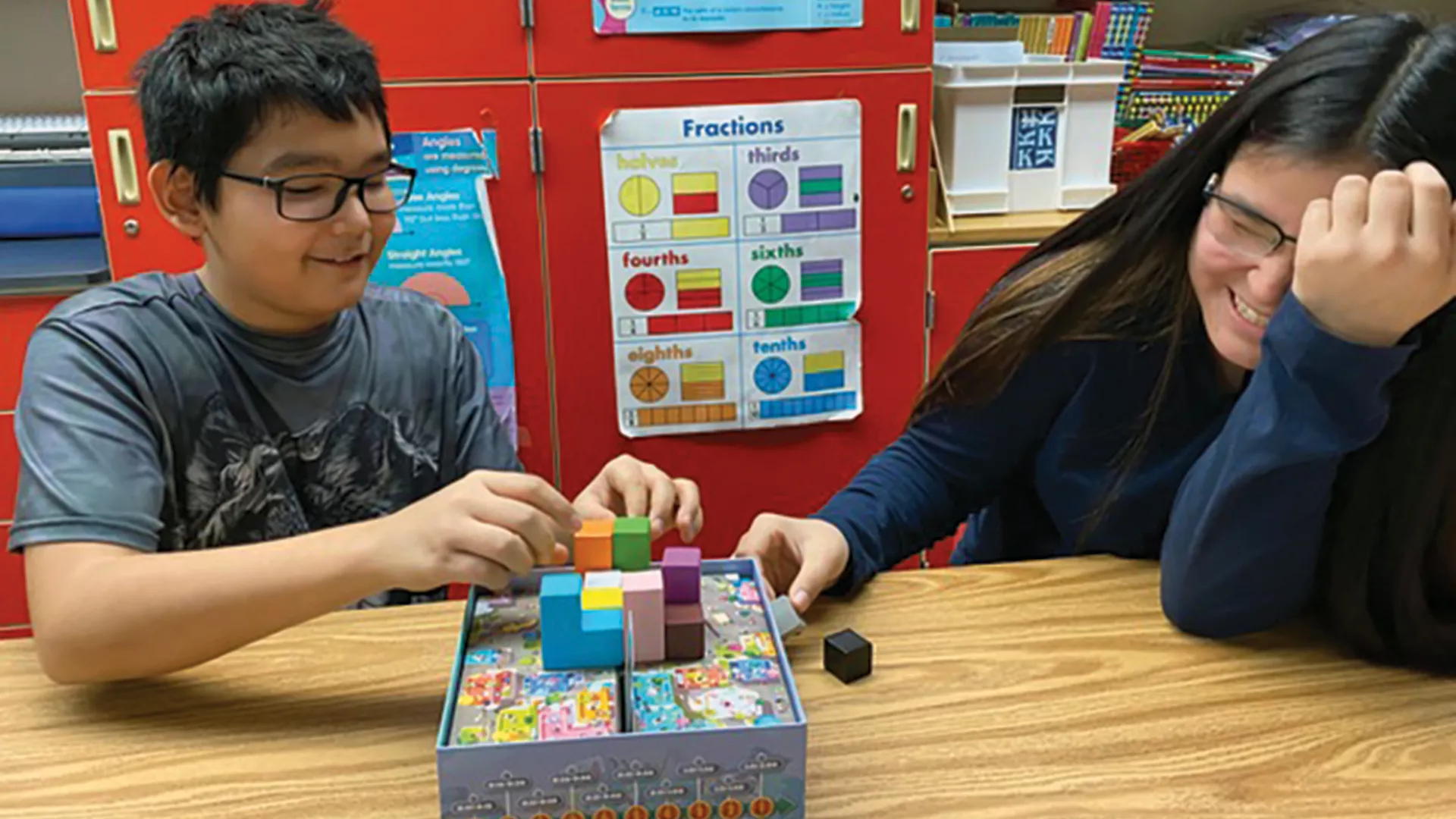 Two middle school students play a board game with cubes in the classroom