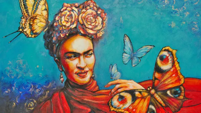 artist rendition of Frida Kahlo dressed in orang with flowers in her hair and butterflies