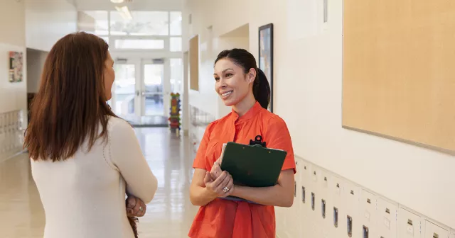 image of two educators talking in a school hallway